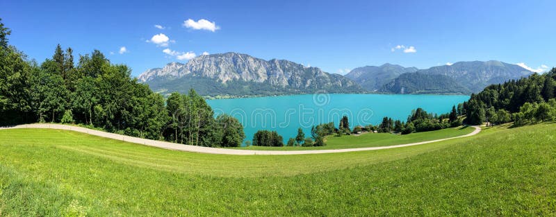 Vista ao lago Attersee com os prados verdes do pasto e cordilheira dos cumes perto de Nussdorf Salzburg, Áustria imagens de stock royalty free Vista ao lago Attersee com os prados verdes do pasto e cordilheira dos cumes perto de Nussdorf Salzburg, Áustria imagens de stock royalty free