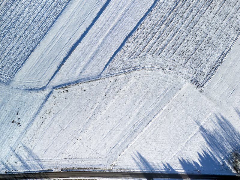 Vista aérea de campos cubiertos de nieve con patrones y sombras creando un tranquilo paisaje invernal. Perfecto para la naturaleza imagen de archivo
