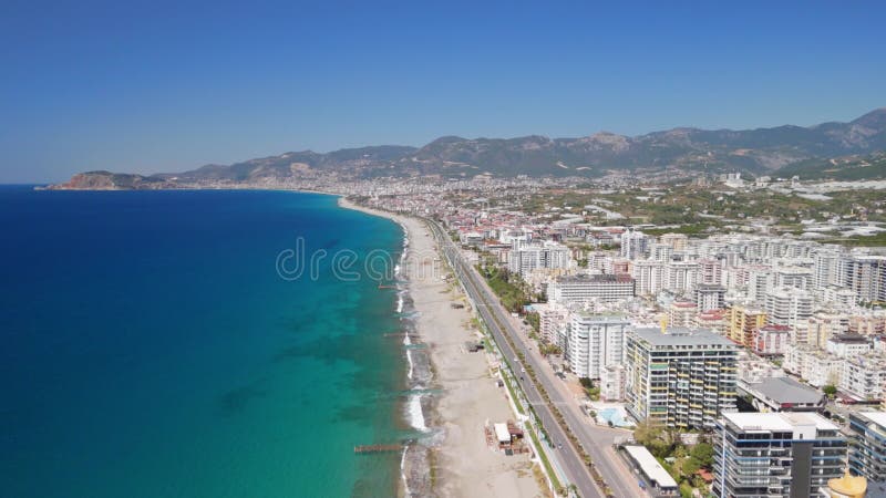 Vista aérea de drones de la ciudad costera con playa y montañas como fondo almacen de metraje de vídeo