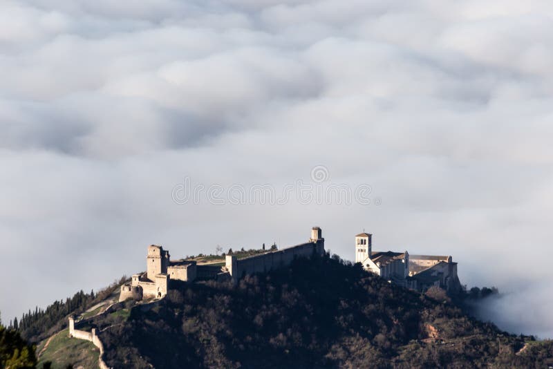 Vista aérea de la ciudad de Asís y de la iglesia de San Francisco sobre un mar de niebla fotografía de archivo Vista aérea de la ciudad de Asís y de la iglesia de San Francisco sobre un mar de niebla fotografía de archivo
