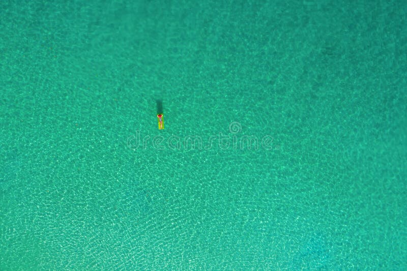 Aerial view of slim woman swimming on the swim mattress in the transparent turquoise sea in Seychelles. Summer seascape with girl, beautiful waves, colorful water. Top view from drone. Aerial view of slim woman swimming on the swim mattress in the transparent turquoise sea in Seychelles. Summer seascape with girl, beautiful waves, colorful water. Top view from drone