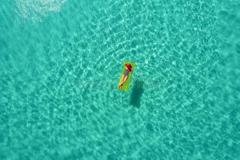 Aerial view of slim woman swimming on the swim mattress in the transparent turquoise sea in Seychelles. Summer seascape with girl, beautiful waves, colorful water. Top view from drone. Aerial view of slim woman swimming on the swim mattress in the transparent turquoise sea in Seychelles. Summer seascape with girl, beautiful waves, colorful water. Top view from drone