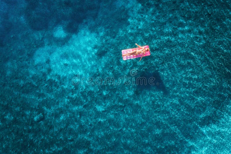 Vista aérea de la natación de la mujer joven en el mattr inflable rosado fotografía de archivo Vista aérea de la natación de la mujer joven en el mattr inflable rosado fotografía de archivo
