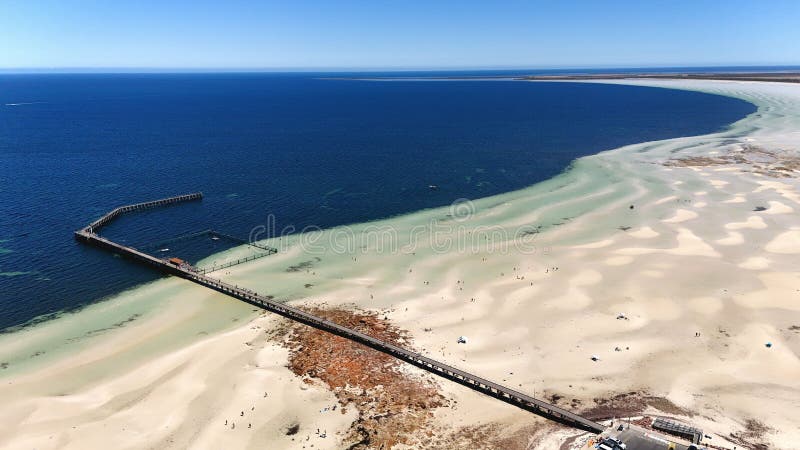 Vista aérea de um píer sobre uma praia arenosa e um oceano. fotos de stock