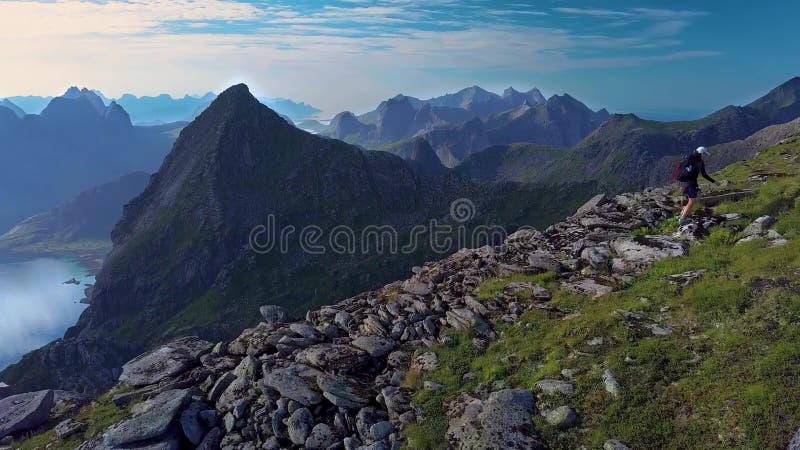 Vista aérea de uma garota com uma mochila sobe em uma serra