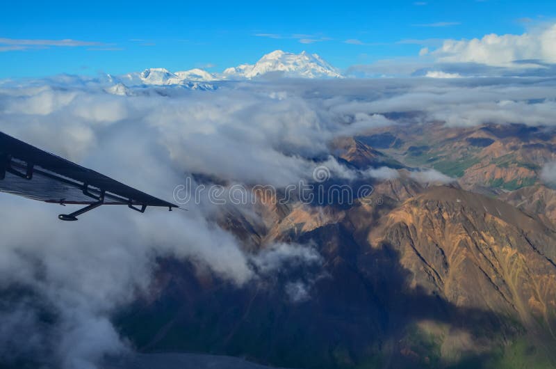 Vista aérea del soporte Denali - pico del mt Mckinley de un avión con las montañas coloridas alrededor y el cielo azul arriba den fotografía de archivo libre de regalías Vista aérea del soporte Denali - pico del mt Mckinley de un avión con las montañas coloridas alrededor y el cielo azul arriba den fotografía de archivo libre de regalías