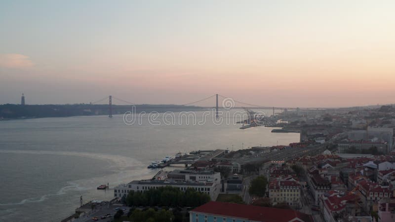 Vista corredera aérea de ponte 25 de abril puente rojo a través del canal del mar en lisboa portugal con casas en la ciudad vieja almacen de metraje de vídeo