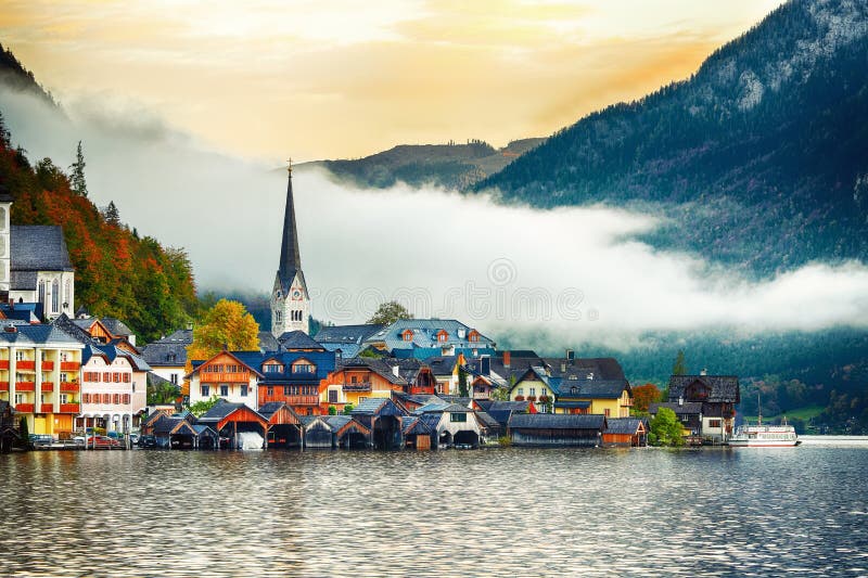 Scenic view of famous Hallstatt mountain village with Hallstatter lake. Foggy autumn sunrise on Hallstatt lake. Location: resort village Hallstatt, Salzkammergut region, Austria, Alps. Europe. Scenic view of famous Hallstatt mountain village with Hallstatter lake. Foggy autumn sunrise on Hallstatt lake. Location: resort village Hallstatt, Salzkammergut region, Austria, Alps. Europe.