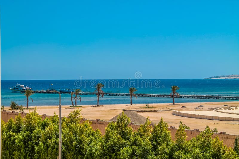 A vista da janela do hotel ao Mar Vermelho, à praia e ao porto sob o céu azul foto de stock A vista da janela do hotel ao Mar Vermelho, à praia e ao porto sob o céu azul foto de stock