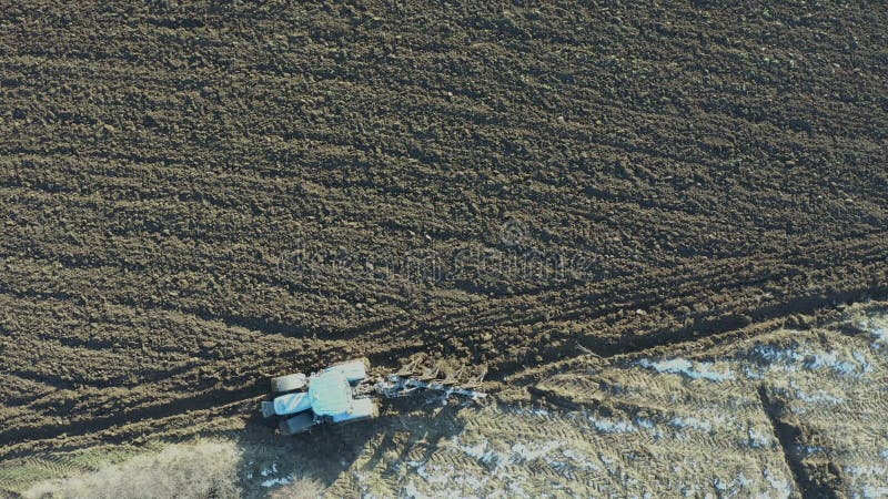 Vista dall'alto del drone di un trattore in movimento, campo di aratura in inverno