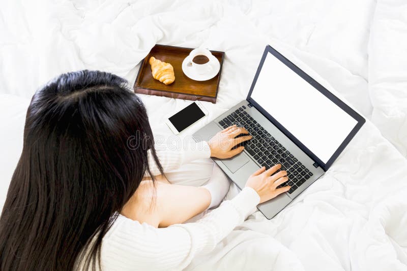 Top view of young asian woman wear white knitwear dress on bed,working with  laptop from bedroom,work online lifestyle relax at home with coffee,Selective focus. Top view of young asian woman wear white knitwear dress on bed,working with  laptop from bedroom,work online lifestyle relax at home with coffee,Selective focus