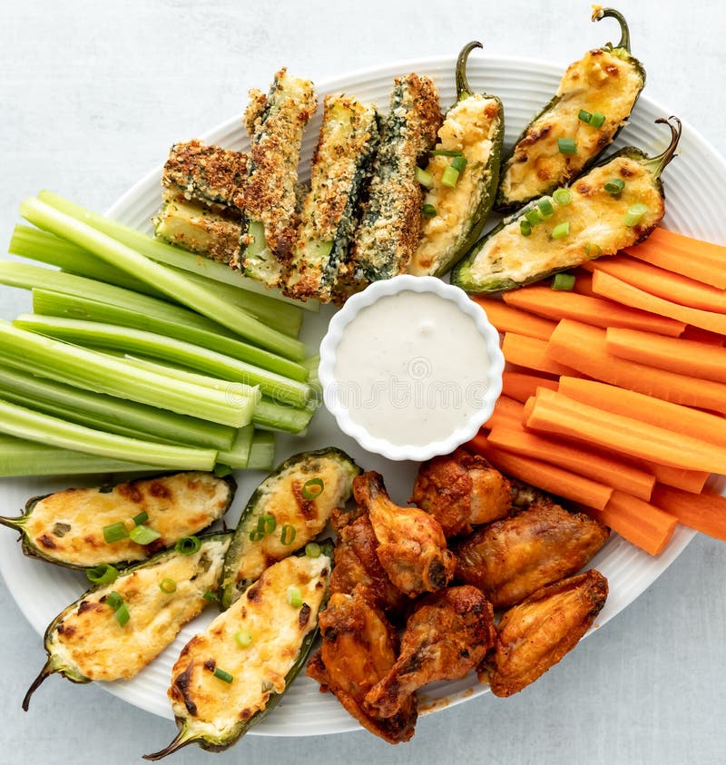 Top down close up view of a finger food appetizer platter including wings, jalapeno poppers and zucchini sticks with ranch dip in the middle. Instagram crop. Top down close up view of a finger food appetizer platter including wings, jalapeno poppers and zucchini sticks with ranch dip in the middle. Instagram crop.