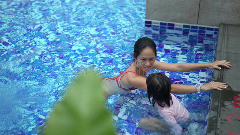 Vista de arriba hacia abajo de la piscina donde disfrutan la madre y la hija chinas asiáticas almacen de video