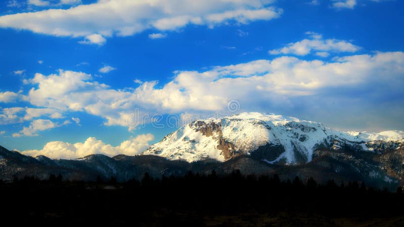 Vista de lapso de tiempo de nubes que fluyen sobre una enorme montaña cubierta de nieve