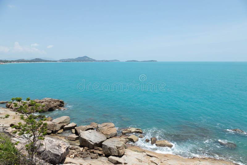 A vista de ondas do mar suporta e costa fantástica da praia rochosa no céu da ilha e do fundo com montanha, natureza selvagem Ter imagem de stock royalty free A vista de ondas do mar suporta e costa fantástica da praia rochosa no céu da ilha e do fundo com montanha, natureza selvagem Ter imagem de stock royalty free