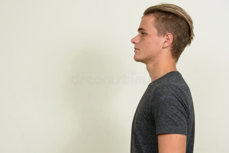 Vista de perfil de um homem bonito com cabelo loiro olhando para a câmera  ao ar livre