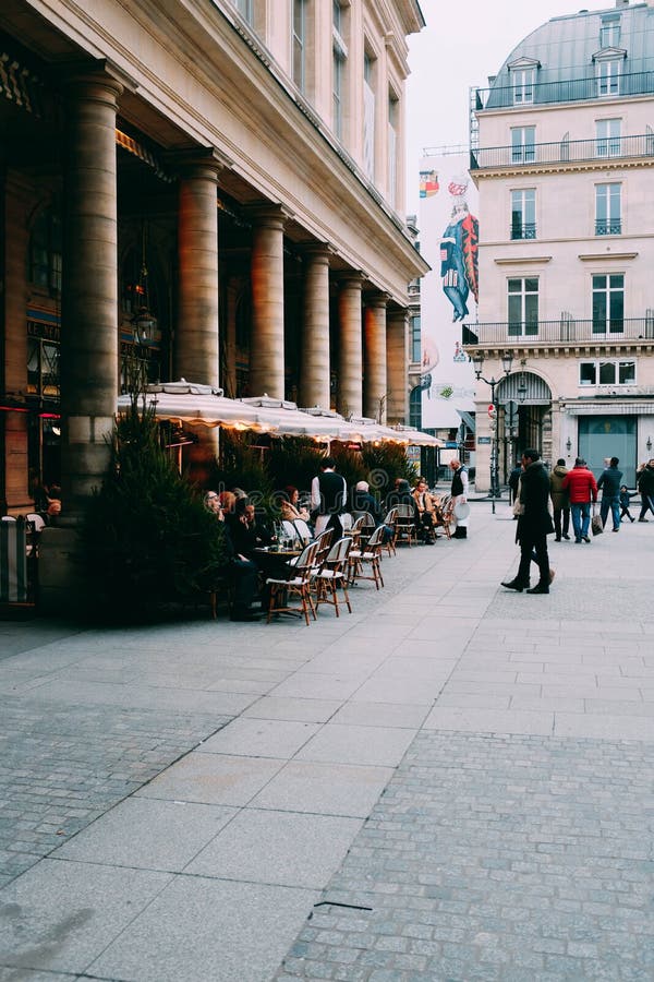 Vista de um café ao ar livre rodeado por belos edifícios modernos durante o dia imagens de stock Vista de um café ao ar livre rodeado por belos edifícios modernos durante o dia imagens de stock