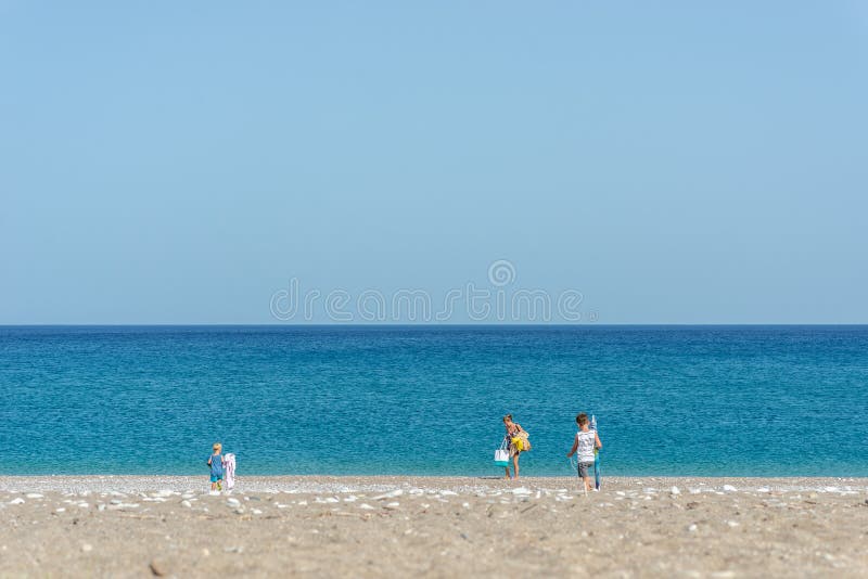Vista de um distante da mãe e das duas crianças que estabelecem seu lugar em uma praia foto de stock royalty free Vista de um distante da mãe e das duas crianças que estabelecem seu lugar em uma praia foto de stock royalty free
