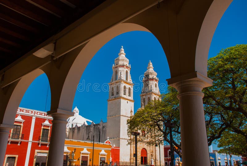 Vista del parque principal a través del arco del edificio de biblioteca en Campeche, México En el fondo es la catedral del la con imagen de archivo