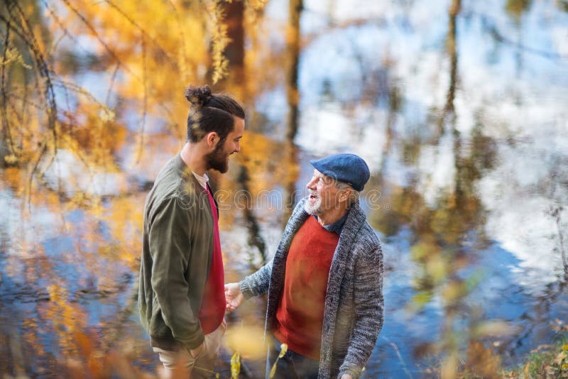 Vista dell'angolo alto del padre senior e della sua condizione del figlio in natura, parlante fotografia stock libera da diritti Vista dell'angolo alto del padre senior e della sua condizione del figlio in natura, parlante fotografia stock libera da diritti