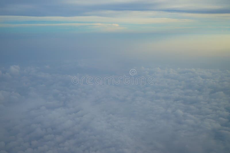 Vista della nuvola bianca astratta vaga con cielo blu e del fondo leggero di alba dalla finestra dell'aeroplano immagine stock Vista della nuvola bianca astratta vaga con cielo blu e del fondo leggero di alba dalla finestra dell'aeroplano immagine stock