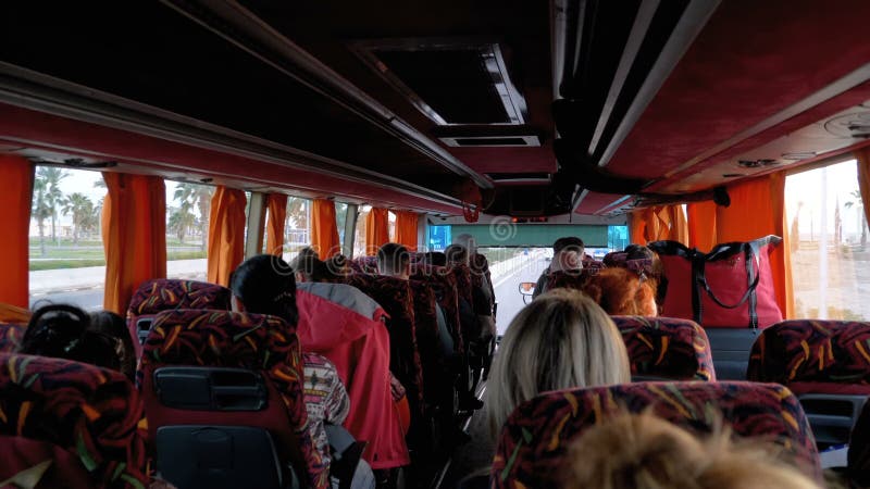 Vista dentro la cabina del bus con i turisti che viaggiano su una strada esotica con le palme