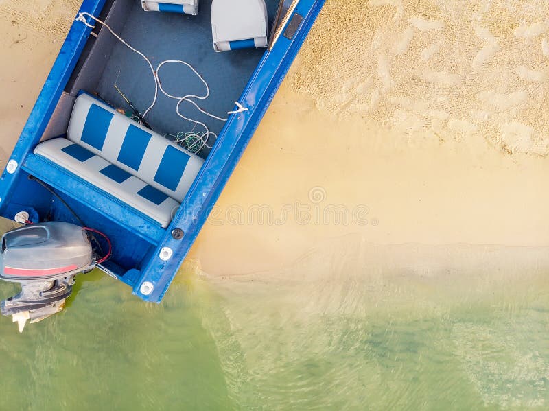 Vista desde arriba en barco de pesca de metal azul con motor amarrado en la playa de arena del lago o rÃo con agua transparente. foto de archivo libre de regalías Vista desde arriba en barco de pesca de metal azul con motor amarrado en la playa de arena del lago o rÃo con agua transparente. foto de archivo libre de regalías