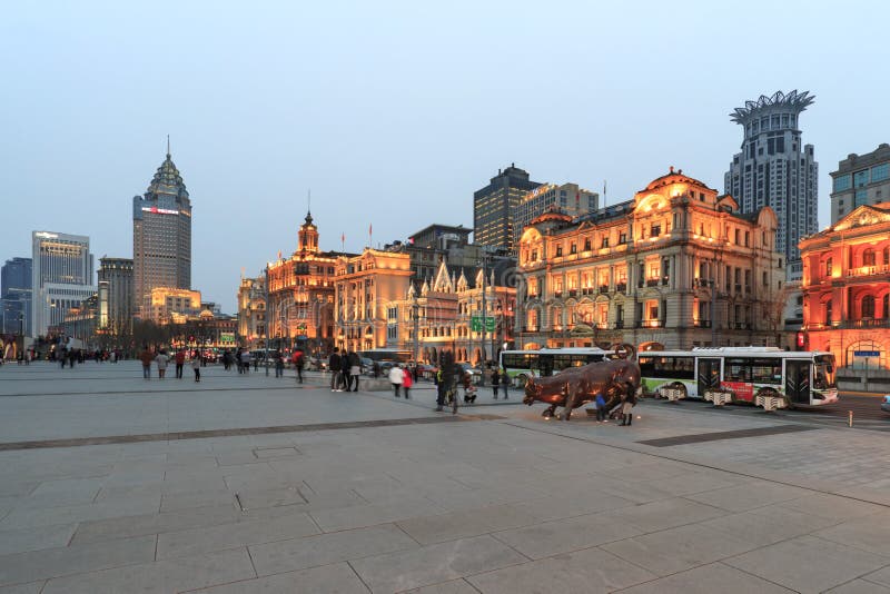 Vista di giorno di Bund di Shanghai ed il toro bronzeo ed alcuni turisti che passano vicino fotografia stock Vista di giorno di Bund di Shanghai ed il toro bronzeo ed alcuni turisti che passano vicino fotografia stock