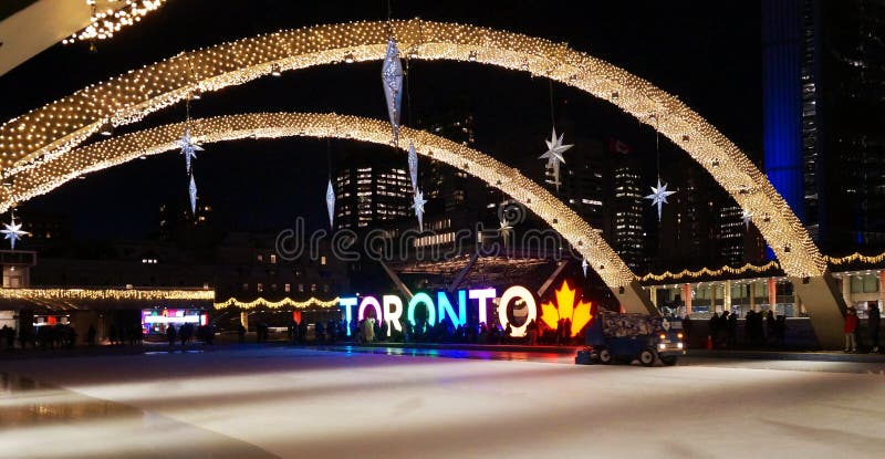 Vista di notte attraverso illuminato brillantemente per la pista di pattinaggio di vigilia del nuovo anno con il segno di TORONTO immagine stock Vista di notte attraverso illuminato brillantemente per la pista di pattinaggio di vigilia del nuovo anno con il segno di TORONTO immagine stock
