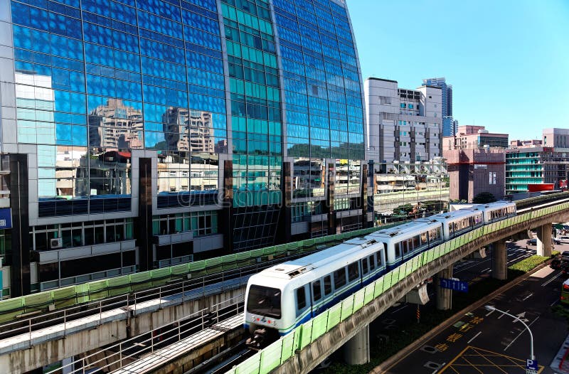 Vista di un treno che viaggia sulle rotaie elevate del sistema della metropolitana di Taipei da una costruzione moderna delle par immagine stock Vista di un treno che viaggia sulle rotaie elevate del sistema della metropolitana di Taipei da una costruzione moderna delle par immagine stock