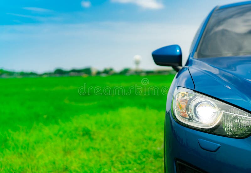 A vista dianteira do carro compacto azul luxuoso de SUV com esporte e projeto moderno estacionou no campo de grama verde com céu imagens de stock A vista dianteira do carro compacto azul luxuoso de SUV com esporte e projeto moderno estacionou no campo de grama verde com céu imagens de stock