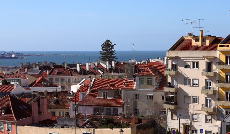 Vista do lado nos telhados das casas sob as telhas vermelhas contra o céu azul com nuvens brancas e o horizonte do oceano foto de stock Vista do lado nos telhados das casas sob as telhas vermelhas contra o céu azul com nuvens brancas e o horizonte do oceano foto de stock