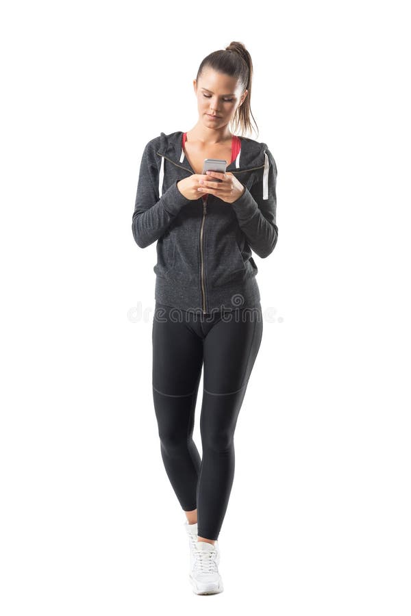 Vista frontale di giovane donna sportiva rilassata di misura che scrive sul telefono cellulare fotografia stock Vista frontale di giovane donna sportiva rilassata di misura che scrive sul telefono cellulare fotografia stock