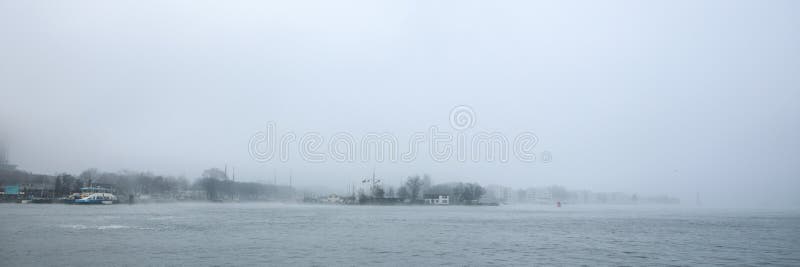 Vista general del canal de la ciudad cerca del embarcadero de la estación central de Amsterdam en día de niebla imagen de archivo Vista general del canal de la ciudad cerca del embarcadero de la estación central de Amsterdam en día de niebla imagen de archivo