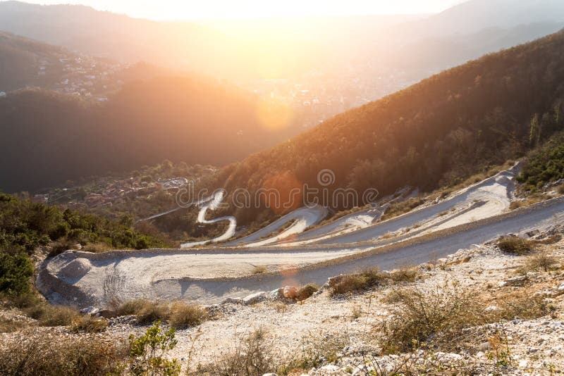Vista granangular de la carretera con curvas, puesta al top de la montaña Brillo de la puesta del sol fotografía de archivo Vista granangular de la carretera con curvas, puesta al top de la montaña Brillo de la puesta del sol fotografía de archivo