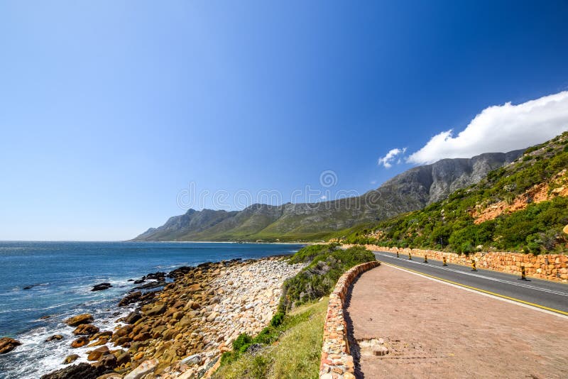 Stunning view of Route 44 in the eastern part of False Bay near Cape Town between Gordon`s Bay and Pringle Bay. Hottentots Holland Mountain range in the background. Viewpoint parking bay on right. Stunning view of Route 44 in the eastern part of False Bay near Cape Town between Gordon`s Bay and Pringle Bay. Hottentots Holland Mountain range in the background. Viewpoint parking bay on right.