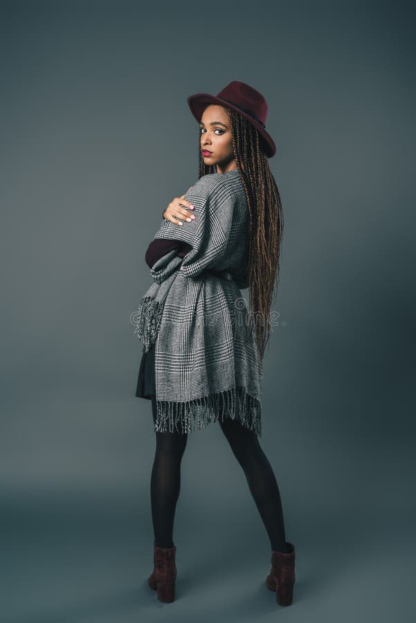 vista integral de la muchacha afroamericana elegante en sombrero y de la rebeca que mira la cámara fotografía de archivo vista integral de la muchacha afroamericana elegante en sombrero y de la rebeca que mira la cámara fotografía de archivo