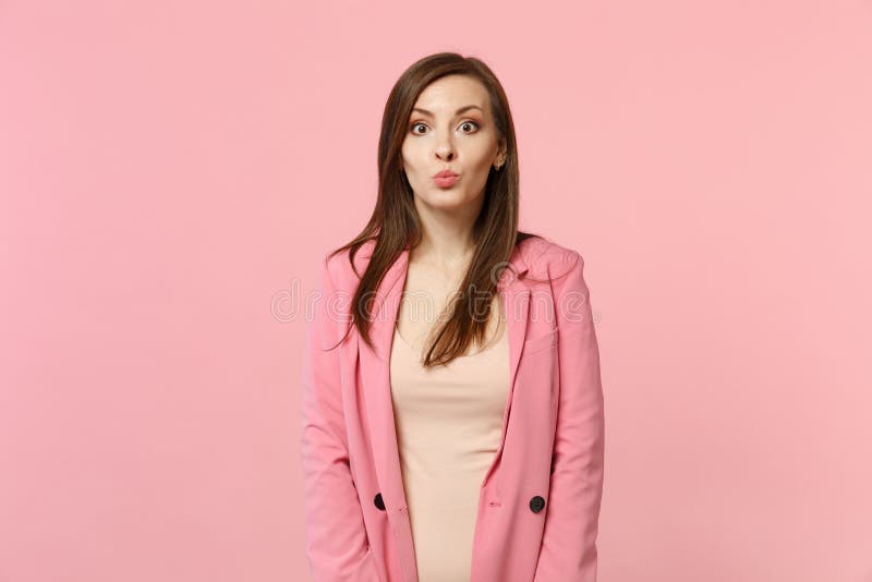 Vista lateral de la mujer joven bonita divertida alegre en la chaqueta que mira la cámara, labios que soplan en la pared rosada e foto de archivo libre de regalías Vista lateral de la mujer joven bonita divertida alegre en la chaqueta que mira la cámara, labios que soplan en la pared rosada e foto de archivo libre de regalías