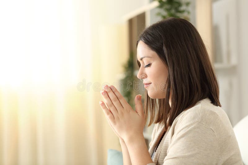 Vista lateral de uma mulher rezando em casa