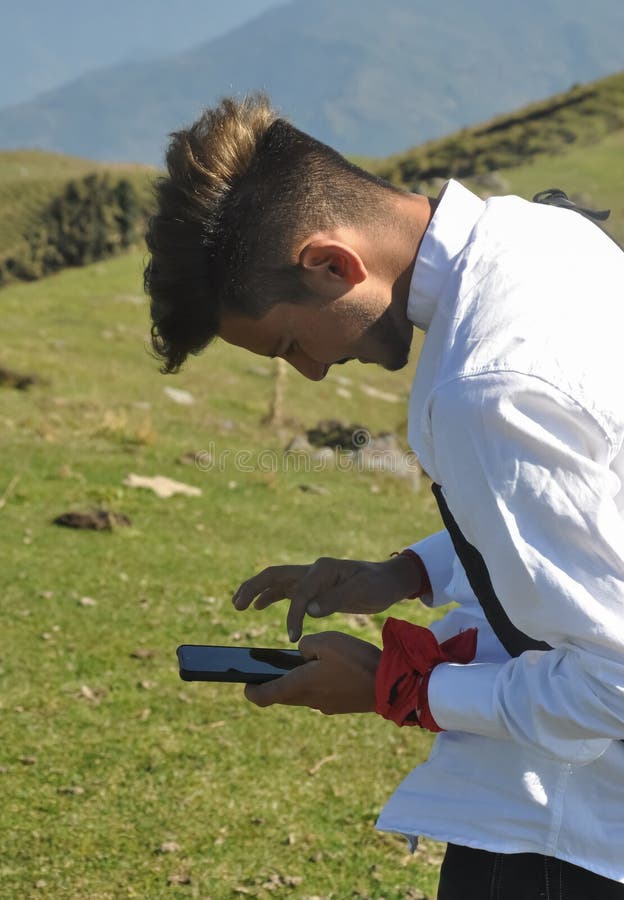 Vista lateral de un joven usando su teléfono en la montaña fotografía de archivo