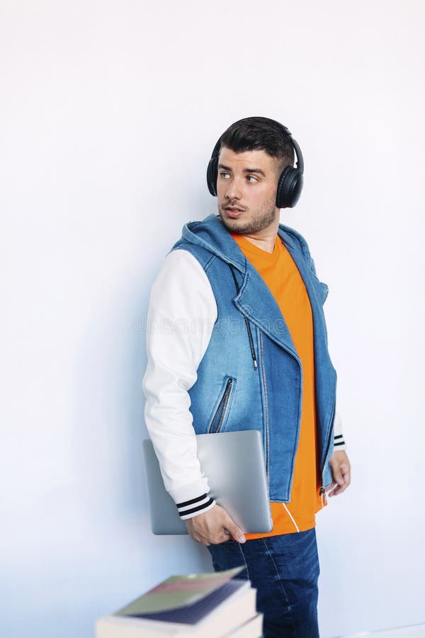 Vista lateral del hombre joven en la ropa casual que se coloca mientras que mira lejos y lleva una PC de la tableta imágenes de archivo libres de regalías Vista lateral del hombre joven en la ropa casual que se coloca mientras que mira lejos y lleva una PC de la tableta imágenes de archivo libres de regalías
