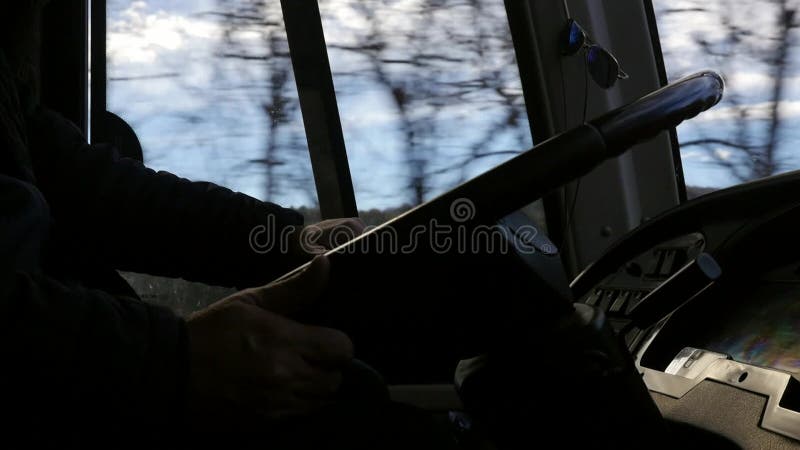 Vista lateral del tablero de mandos de autobús o camioneta y las manos de los conductores sobre el volante cuando se conduce por a