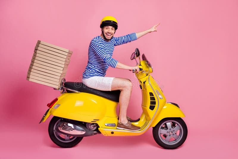 Vista lateral do perfil dele, o bonito bonito e bonito e alegre e alegre cara dirigindo moto entregando pizza apontando