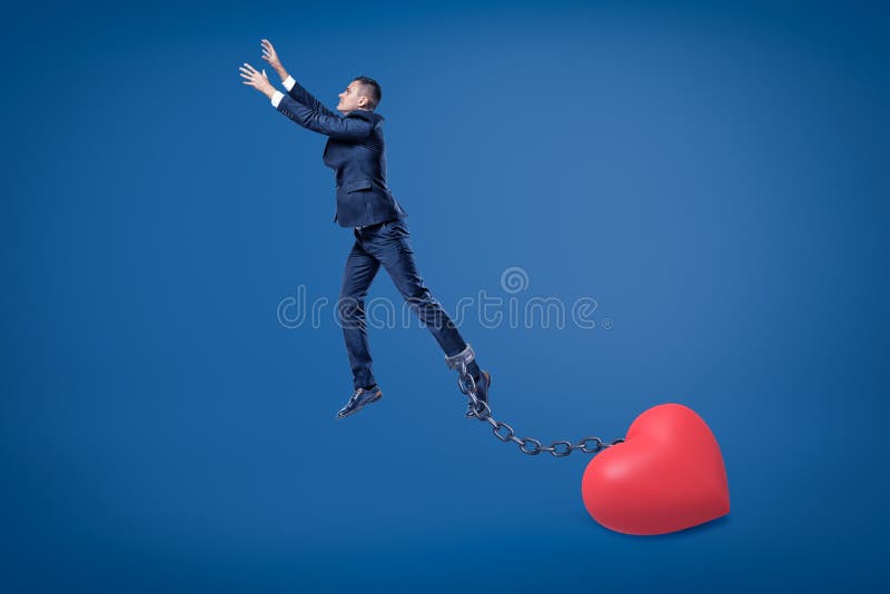 Side view of businessman in mid-air chained to big Valentine heart on the ground. Relationship problems. Men need more space. Love cannot be forced. Side view of businessman in mid-air chained to big Valentine heart on the ground. Relationship problems. Men need more space. Love cannot be forced.