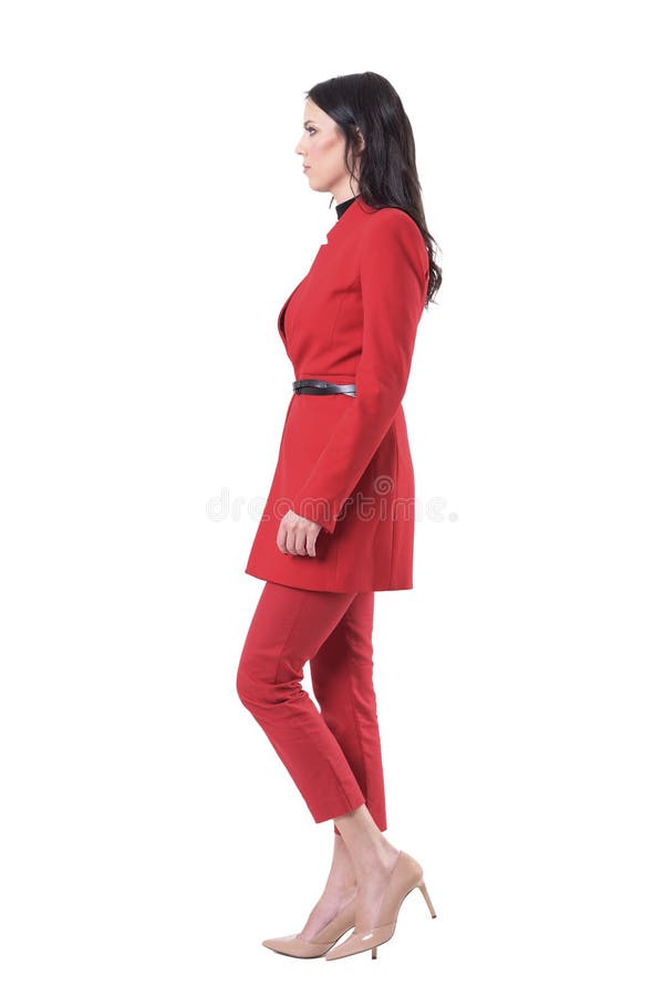 Vista laterale della donna seria sicura di affari in vestito rosso che cammina e che guarda avanti fotografie stock libere da diritti Vista laterale della donna seria sicura di affari in vestito rosso che cammina e che guarda avanti fotografie stock libere da diritti