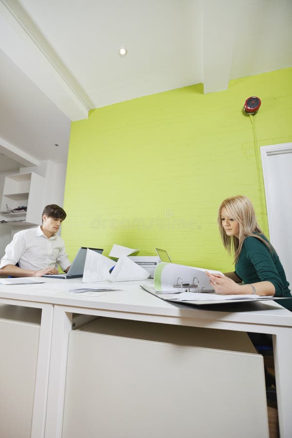 Vista laterale di lavoro occupato delle giovani persone di affari allo scrittorio immagine stock