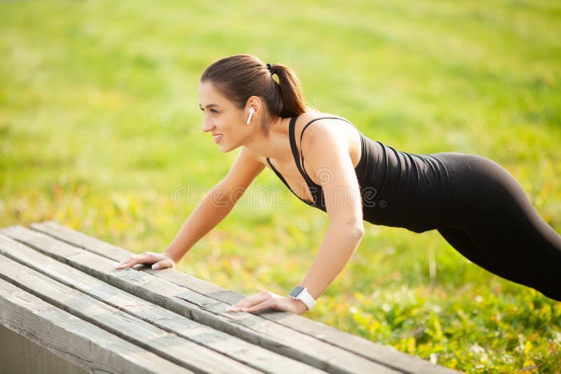 Vista laterale di un asiatico motivato Ritratto di bella donna sportiva 20s in abiti sportivi che fanno spinta-UPS ed ascoltanti fotografia stock libera da diritti Vista laterale di un asiatico motivato Ritratto di bella donna sportiva 20s in abiti sportivi che fanno spinta-UPS ed ascoltanti fotografia stock libera da diritti