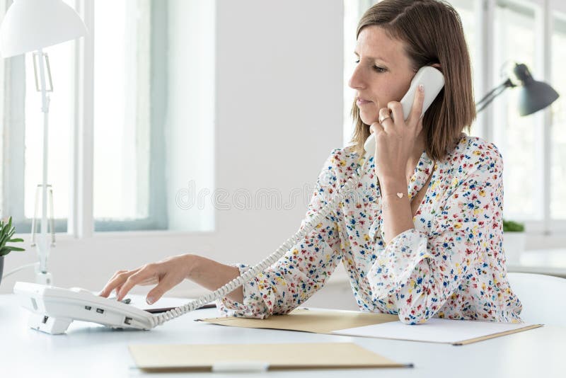 Vista laterale di un numero di telefono di composizione della donna fotografia stock Vista laterale di un numero di telefono di composizione della donna fotografia stock