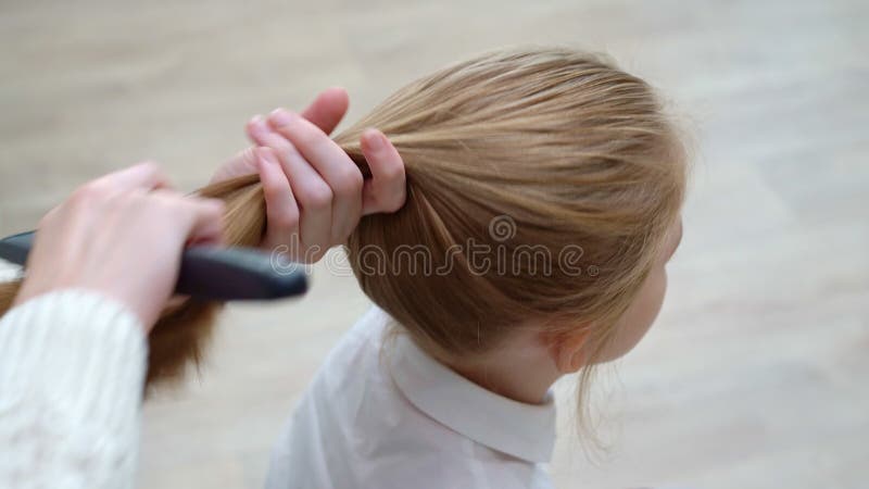 Vista laterale. sbadiglia di una ragazza della scuola, mentre la madre pettina i capelli e gli involucri di coda stock footage