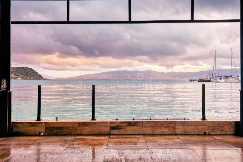 Vista marítima e marina ao pôr do sol enquadrada pelas colunas de um terraço fotografia de stock Vista marítima e marina ao pôr do sol enquadrada pelas colunas de um terraço fotografia de stock